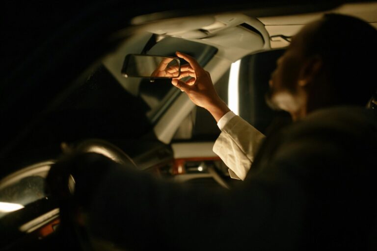 driver adjusting mirror at night