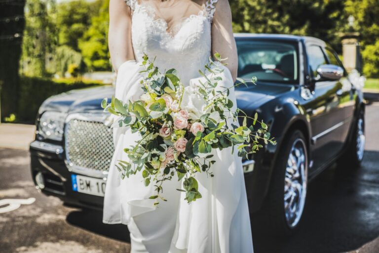 woman in wedding dress in front of car